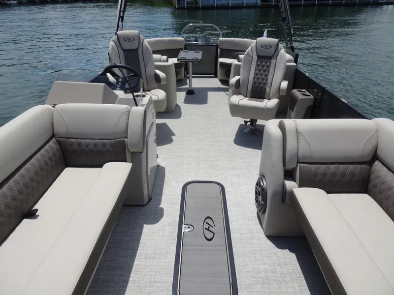 Slide: The Image of 2023 Harris Sunliner 250 pontoon boat interior with luxurious seating and steering wheel on water. - 20
