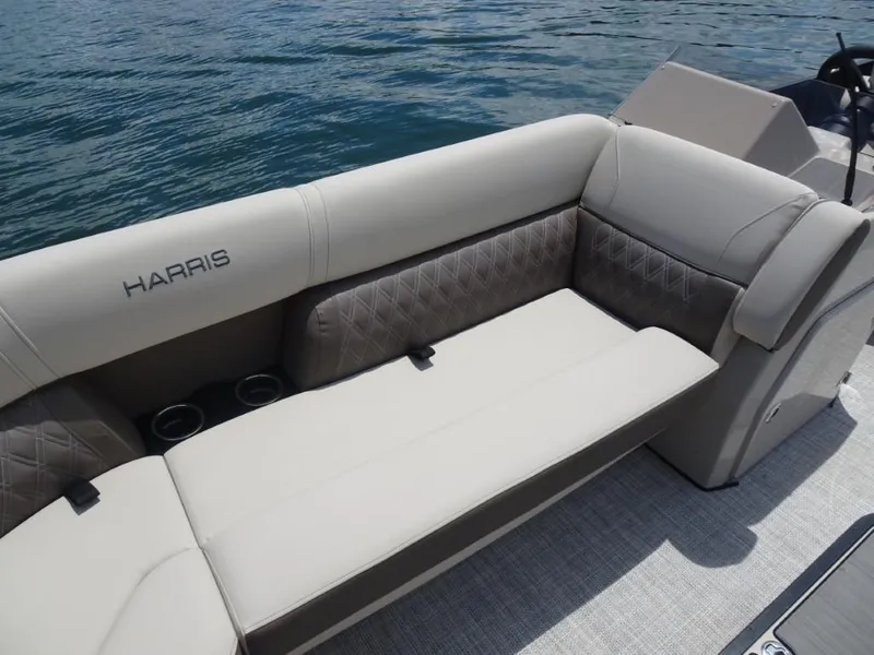 Slide: The Image of 2023 Harris Sunliner 250 boat interior with luxurious seating and cup holders on water. - 21