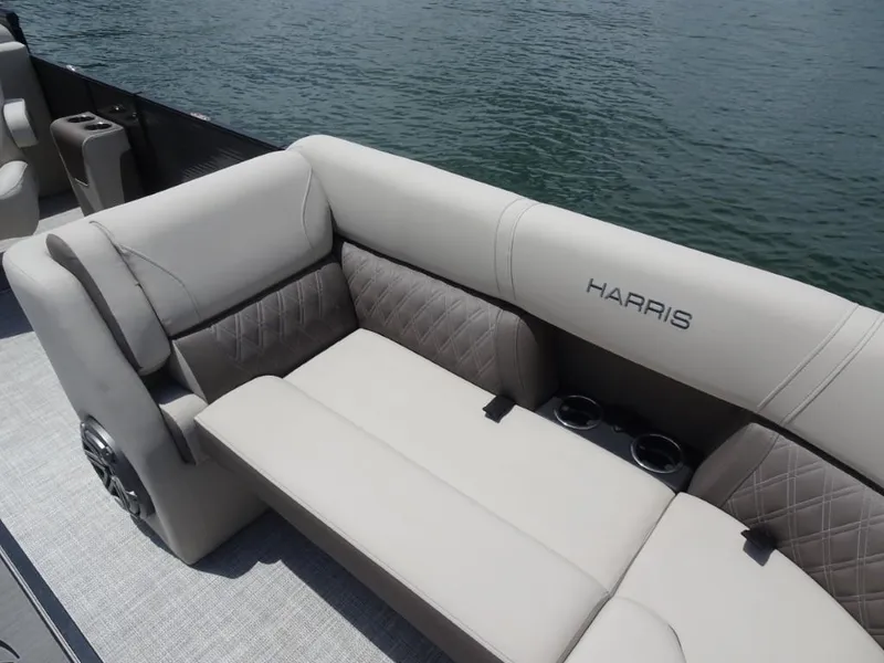 Slide: The Image of 2023 Harris Sunliner 250 boat interior with plush seating and cup holders by the water. - 22