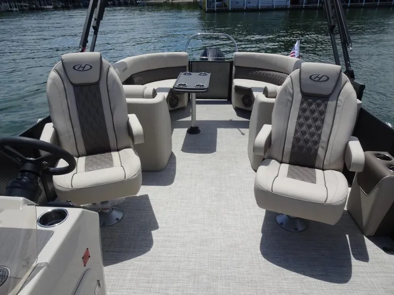Slide: The Image of 2023 Harris Sunliner 250 boat interior with plush seating on a calm lake. - 23