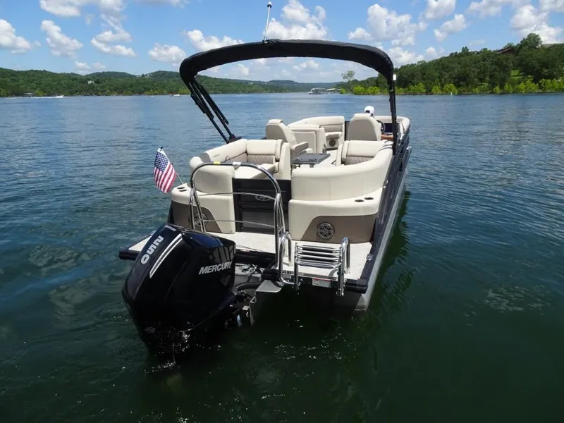 Slide: The Image of 2023 Harris Sunliner 250 pontoon boat on a scenic lake with clear skies. - 3
