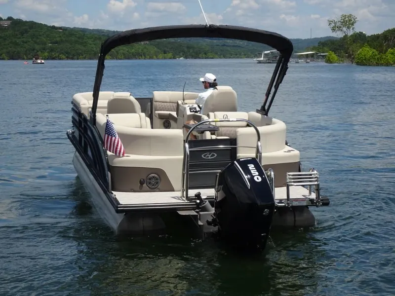 Slide: The Image of 2023 Harris Sunliner 250 pontoon boat cruising on a scenic lake. - 4
