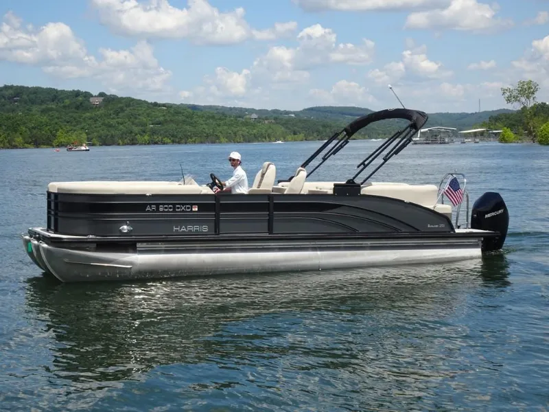 Slide: The Image of 2023 Harris Sunliner 250 pontoon boat on a lake with scenic background. - 6