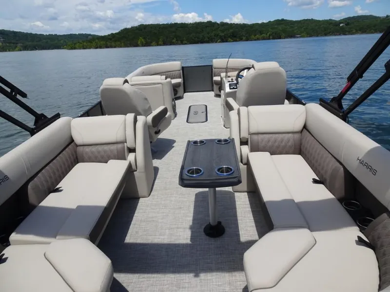 Slide: The Image of 2023 Harris Sunliner 250 pontoon boat with spacious seating on a serene lake. - 9