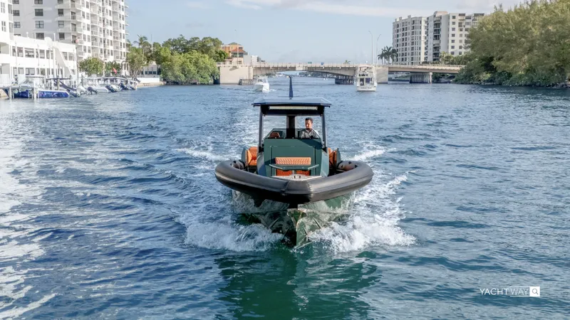 Slide: The Image of 2025 Skipper-BSK 38 boat cruising in urban waterway with buildings and bridge in background. - 19