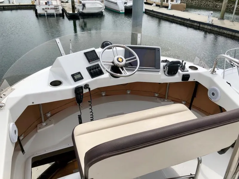 Slide: The Image of 2014 Ranger Tugs R-31CB helm with steering wheel, controls, and navigation equipment at marina. - 10