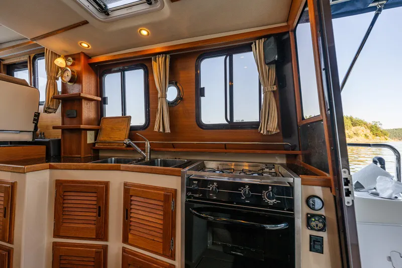 Slide: The Image of 2014 Ranger Tugs R-31CB boat interior with wooden cabinetry and kitchen appliances. - 18
