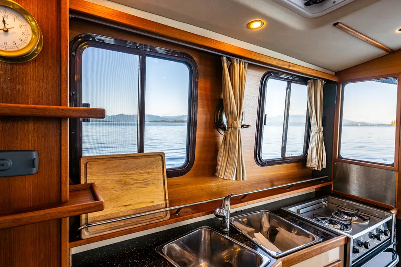 Slide: The Image of Cozy 2014 Ranger Tugs R-31CB kitchen with wood accents and ocean view. - 25