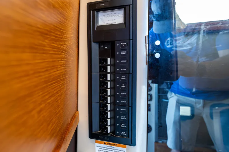 Slide: The Image of Electrical panel on 2014 Ranger Tugs R-31CB boat, featuring various switches and a voltage meter. - 27