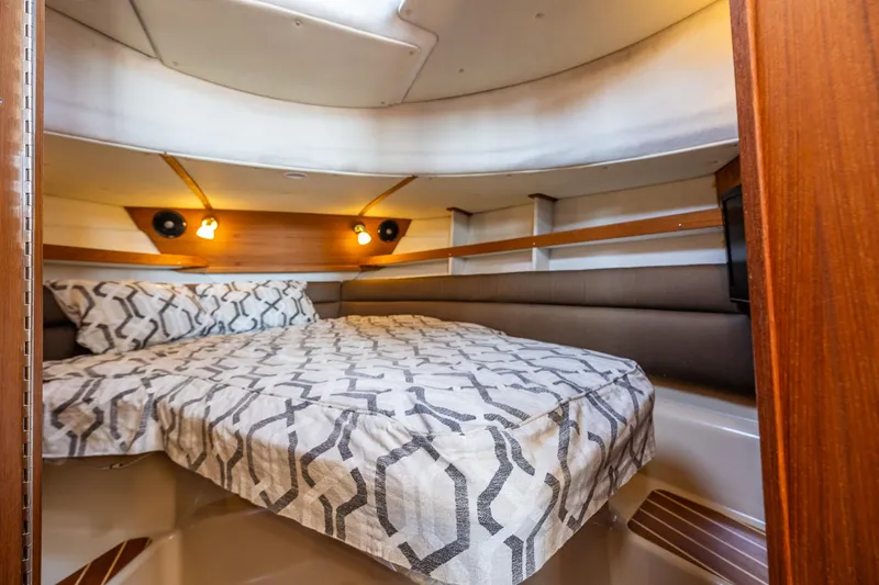 Slide: The Image of Cozy cabin interior of 2014 Ranger Tugs R-31CB with patterned bedding and warm lighting. - 29