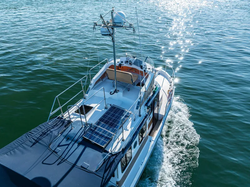 Slide: The Image of 2014 Ranger Tugs R-31CB cruising on sparkling water, featuring solar panels and radar equipment. - 3