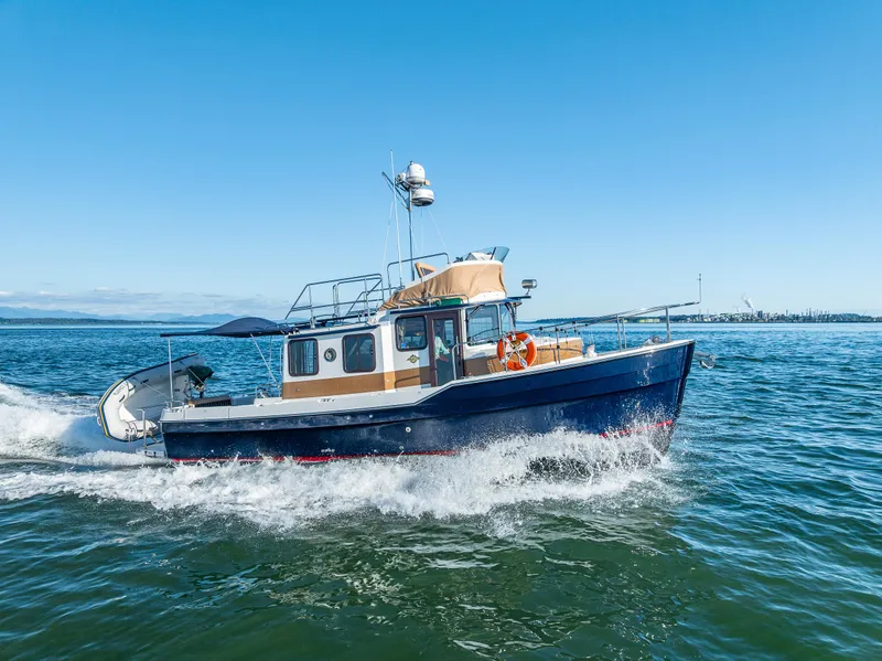 Slide: The Image of 2014 Ranger Tugs R-31CB cruising on open water under clear blue skies. - 5