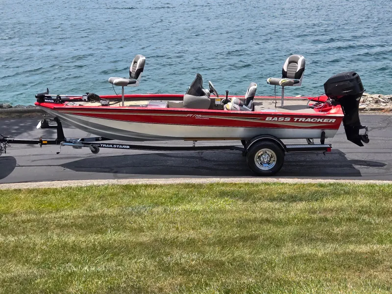 The Image of 2004 Tracker Pro Team 175 bass boat on trailer by a lake. - 0
