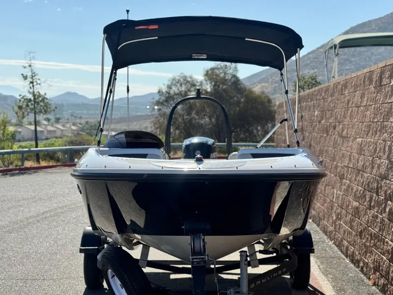 Slide: The Image of 2019 Bayliner Element E16 boat on trailer, parked outdoors with scenic mountain backdrop. - 2