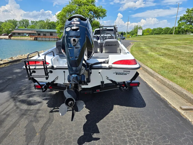 Slide: The Image of 1996 Javelin 360 FS boat with outboard motor, parked near a lake on a sunny day. - 2
