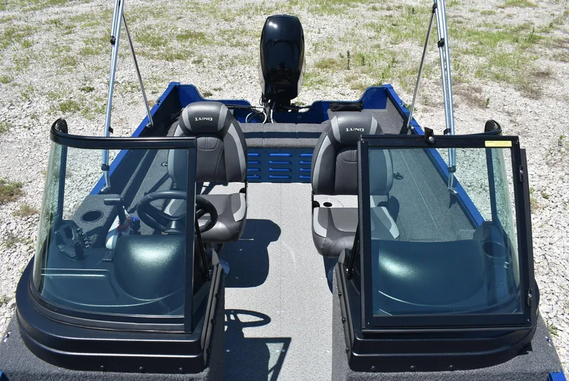 Slide: The Image of 2022 Lund 1650 Angler Sport boat interior with dual seats and windshield, parked on gravel. - 8