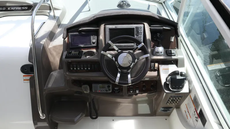 Slide: The Image of 2012 Cruisers Yachts 350 Express helm with steering wheel and navigation controls. - 5