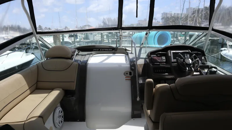 Slide: The Image of 2012 Cruisers Yachts 350 Express cockpit with helm, seating, and marina view. - 7