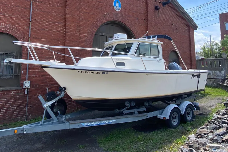 Slide: The Image of 2009 Parker 2120 Sport Cabin boat on trailer, parked by a brick building. - 0