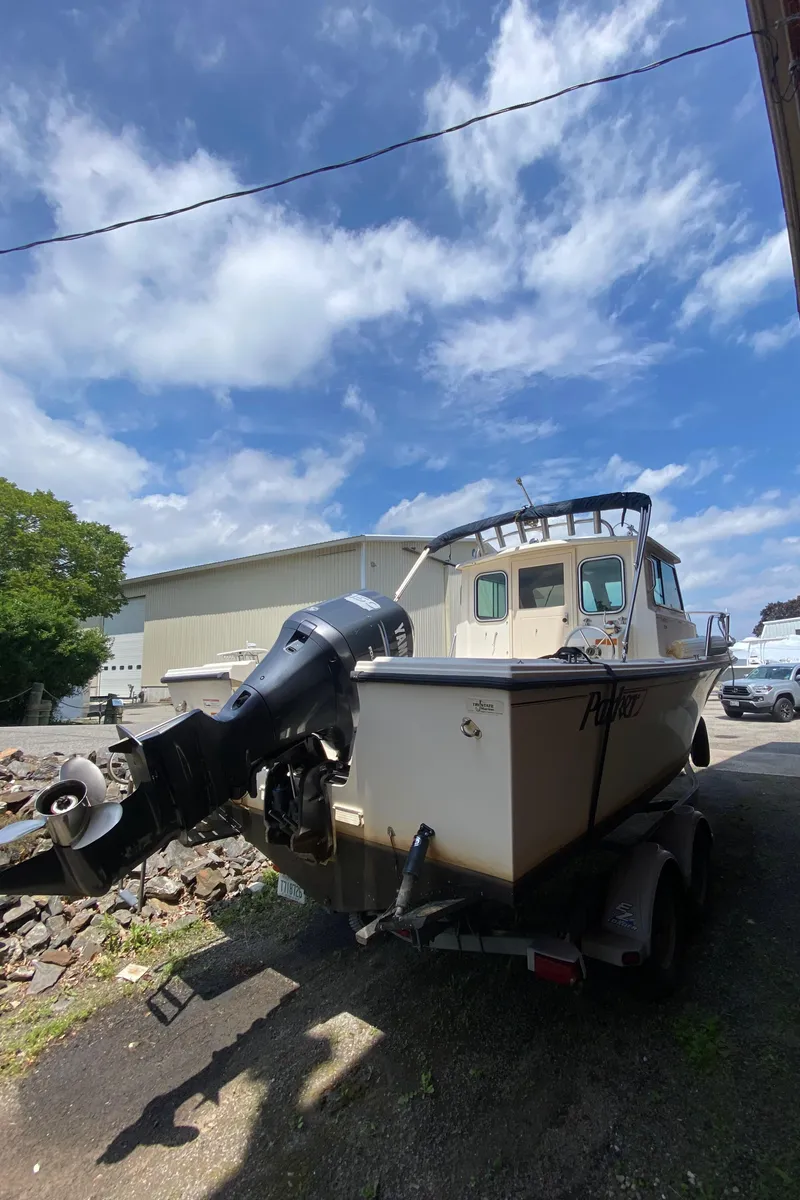 Slide: The Image of 2009 Parker 2120 Sport Cabin boat on trailer under a partly cloudy sky. - 3