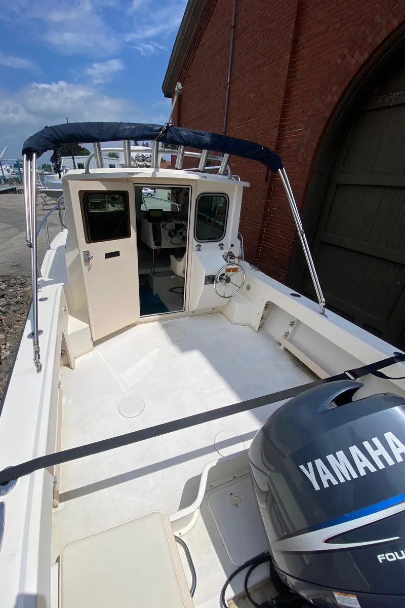Slide: The Image of 2009 Parker 2120 Sport Cabin boat with Yamaha engine, docked near a brick building. - 5