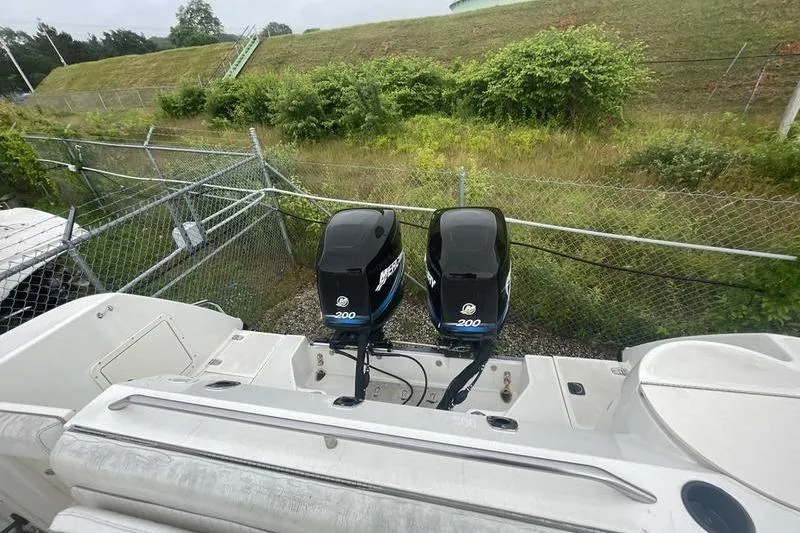 Slide: The Image of Boston Whaler 28 Outrage 2000 with dual Mercury 200 engines, parked near a fence. - 4
