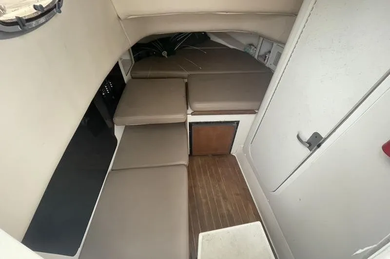 Slide: The Image of 2000 Boston Whaler 28 Outrage cabin interior with cushioned seating and wooden flooring. - 6