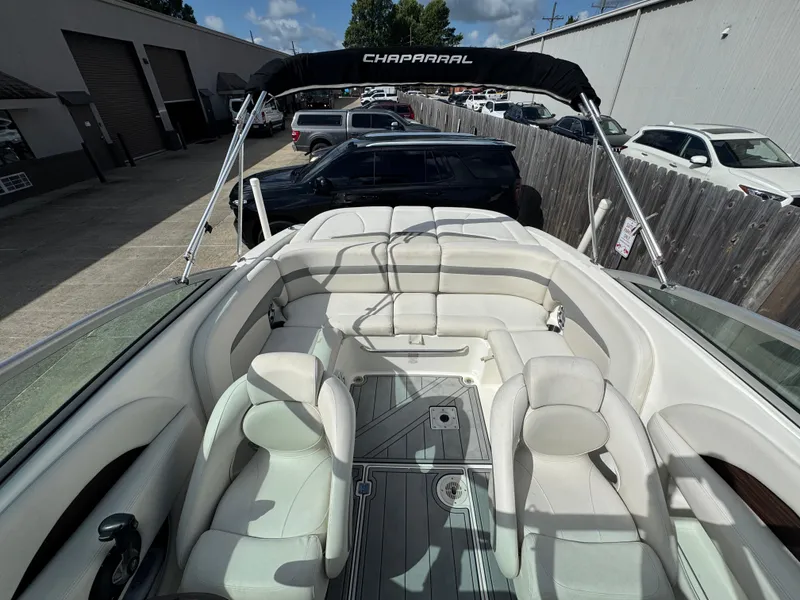 Slide: The Image of 2006 Chaparral 236 SSi boat interior with white seating and bimini top, parked outdoors. - 16