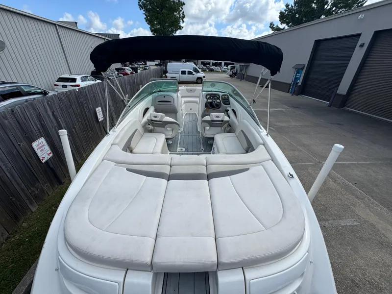 Slide: The Image of 2006 Chaparral 236 SSi boat with spacious seating and canopy in a parking area. - 8