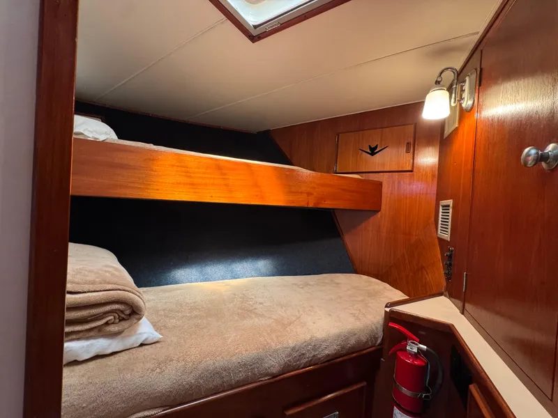 Slide: The Image of 1981 Bertram 58 Flybridge Motor Yacht cabin with wooden bunk beds and cozy lighting. - 21