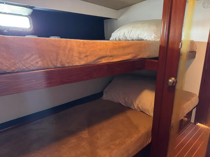 Slide: The Image of Bunk beds in 1981 Bertram 58 Flybridge Motor Yacht cabin, featuring wooden accents and soft lighting. - 26