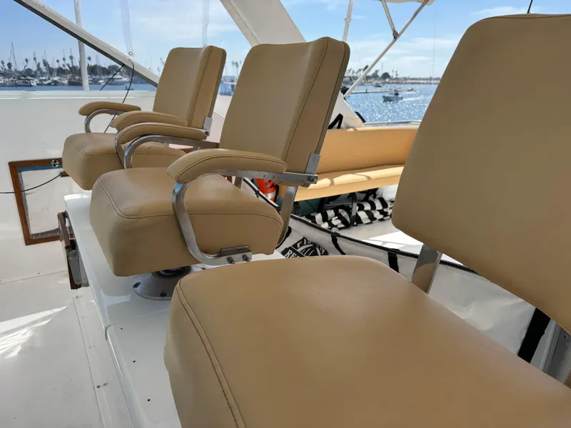 Slide: The Image of Beige captain chairs on 1981 Bertram 58 Flybridge Motor Yacht, overlooking marina. - 34