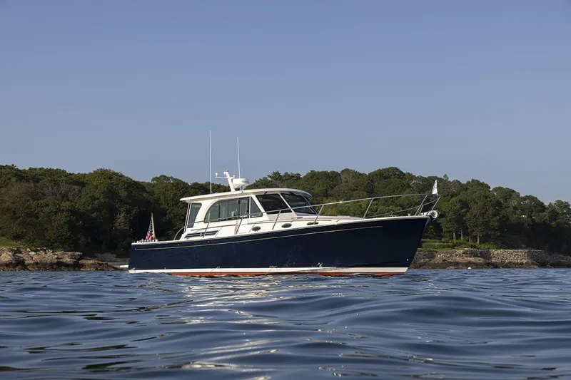 The Image of 2026 Back Cove 412 yacht on calm water with scenic shoreline backdrop. - 0