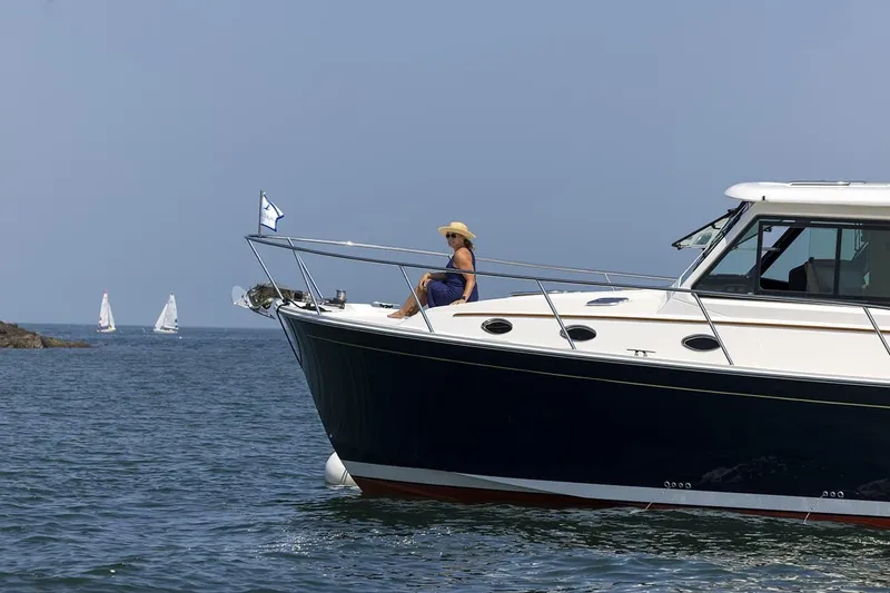 Slide: The Image of 2026 Back Cove 412 yacht cruising with person relaxing on deck, sailboats in background. - 17