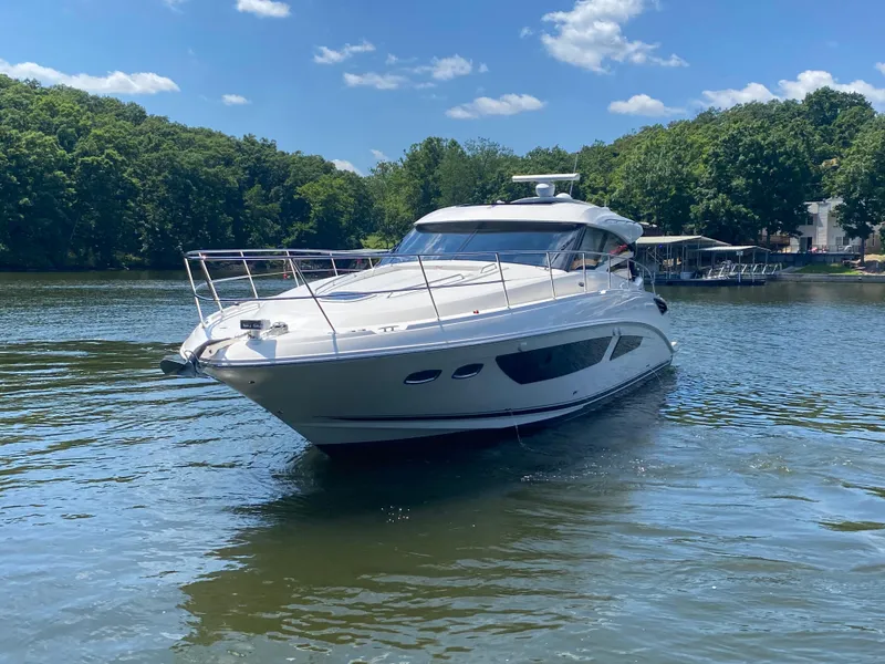 Slide: The Image of 2015 Sea Ray 470 Sundancer yacht cruising on a serene lake under a clear blue sky. - 2