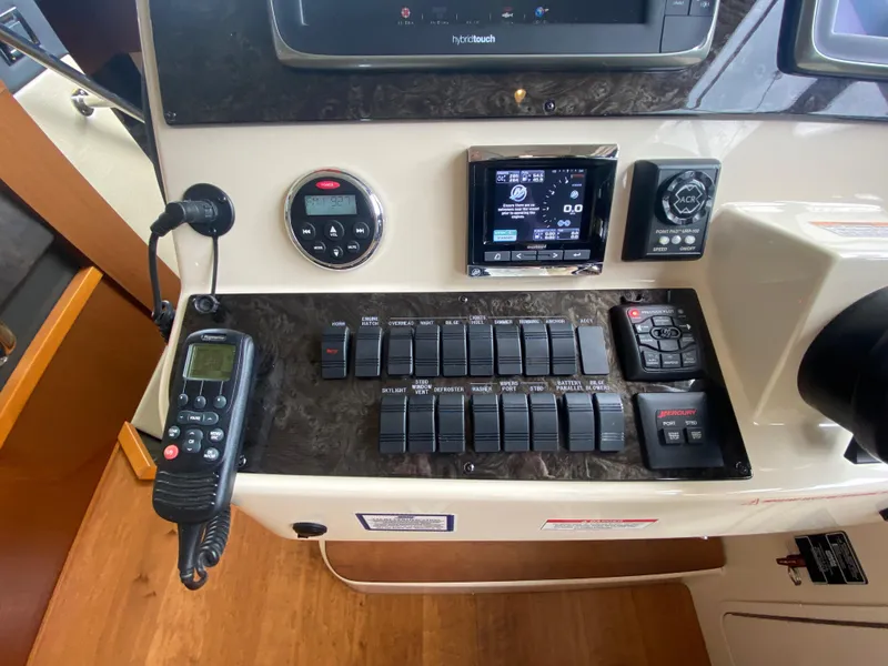 Slide: The Image of Control panel of a 2015 Sea Ray 470 Sundancer yacht with various switches and displays. - 26