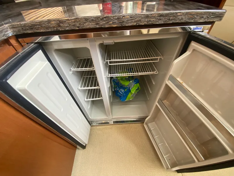 Slide: The Image of Open refrigerator inside 2015 Sea Ray 470 Sundancer yacht, showing shelves and bottled water. - 29