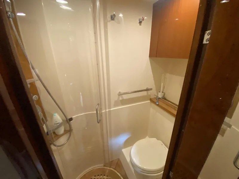 Slide: The Image of 2015 Sea Ray 470 Sundancer bathroom with shower, toilet, and wooden cabinetry. - 42