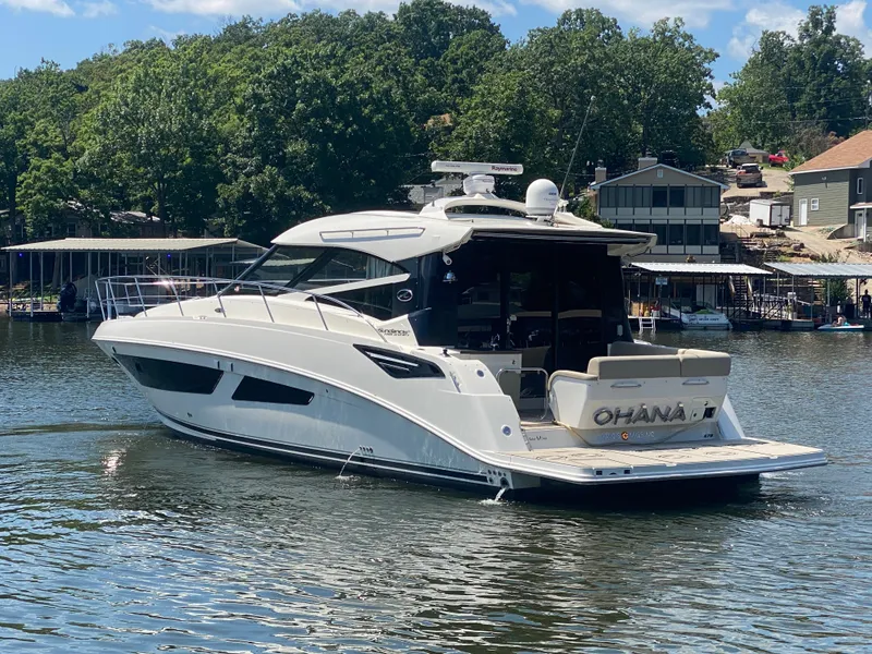 Slide: The Image of 2015 Sea Ray 470 Sundancer yacht on a lake, surrounded by trees and houses. - 5