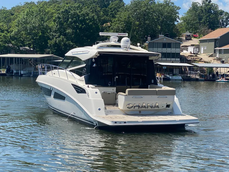 Slide: The Image of 2015 Sea Ray 470 Sundancer yacht on a serene lake with lush greenery. - 6