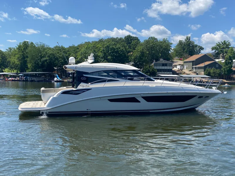 Slide: The Image of 2015 Sea Ray 470 Sundancer yacht on a sunny lake with trees and houses in the background. - 9