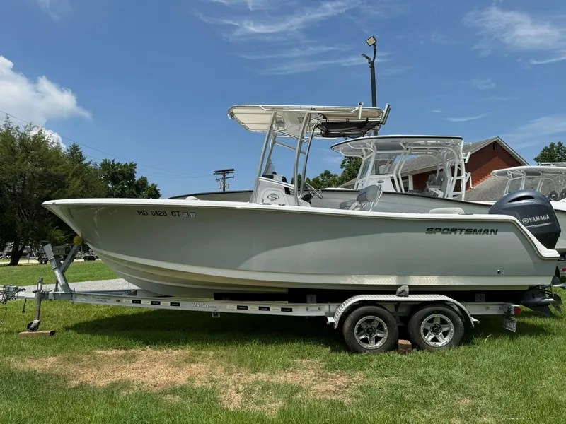 Slide: The Image of 2019 Sportsman Open 232 Center Console boat on trailer, parked on grass. - 1
