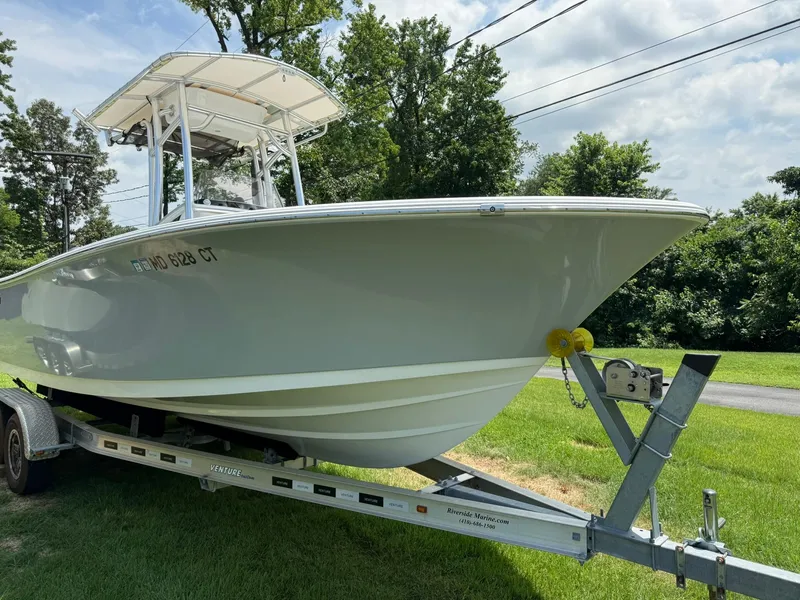 Slide: The Image of 2019 Sportsman Open 232 Center Console boat on trailer, parked on grass. - 2