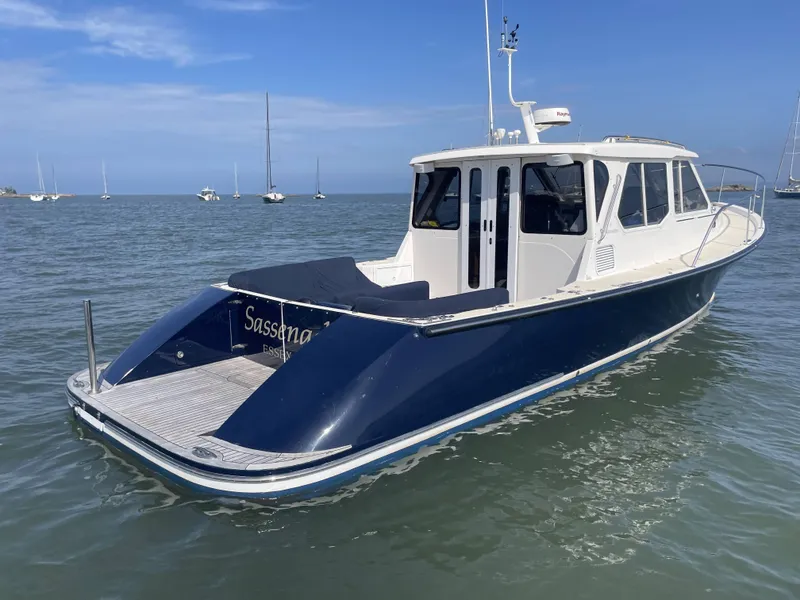 Slide: The Image of 2007 True North 38 boat on calm water, blue and white design, clear sky background. - 2