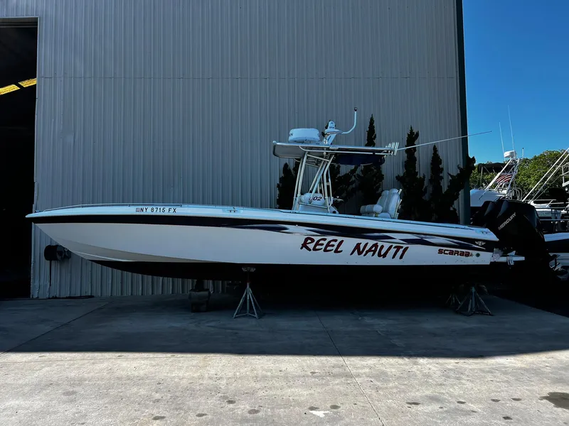 The Image of 1998 Wellcraft Scarab Sport 302 boat named "Reel Nauti" on display outside a building. - 0
