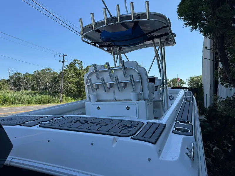 Slide: The Image of 1998 Wellcraft Scarab Sport 302 boat with rod holders and canopy, parked near greenery. - 2