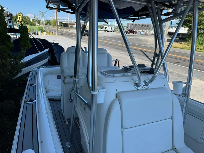 Slide: The Image of 1998 Wellcraft Scarab Sport 302 boat with white seating and metal framework, docked near a road. - 20