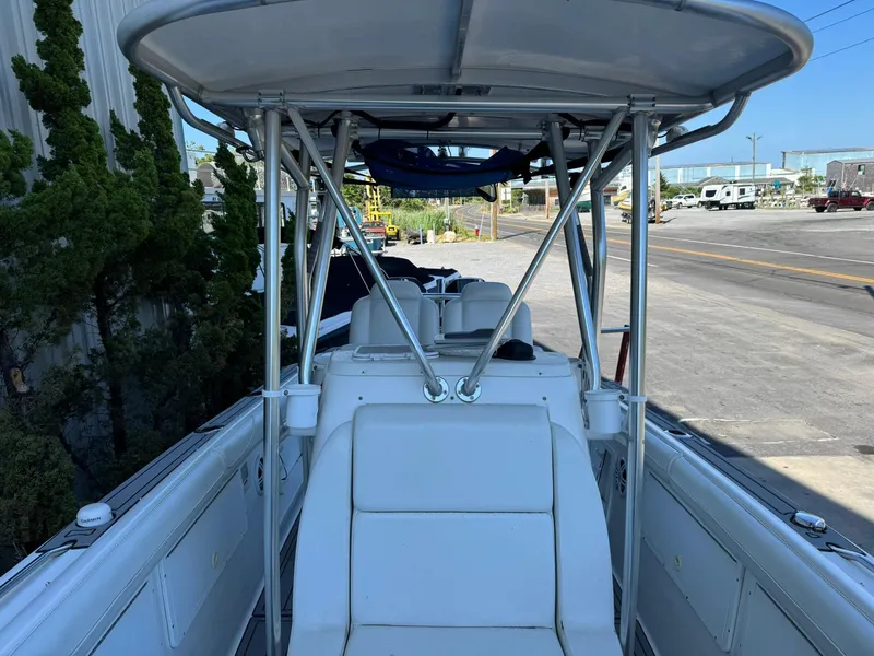 Slide: The Image of 1998 Wellcraft Scarab Sport 302 boat with T-top and seating, parked near a road. - 27