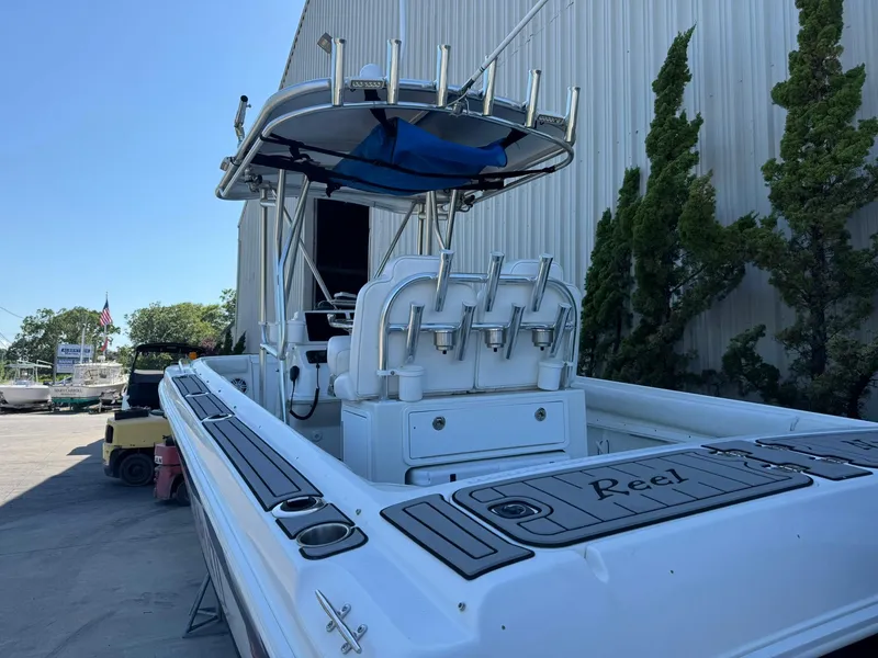 Slide: The Image of 1998 Wellcraft Scarab Sport 302 boat with fishing rod holders, docked near a warehouse. - 3