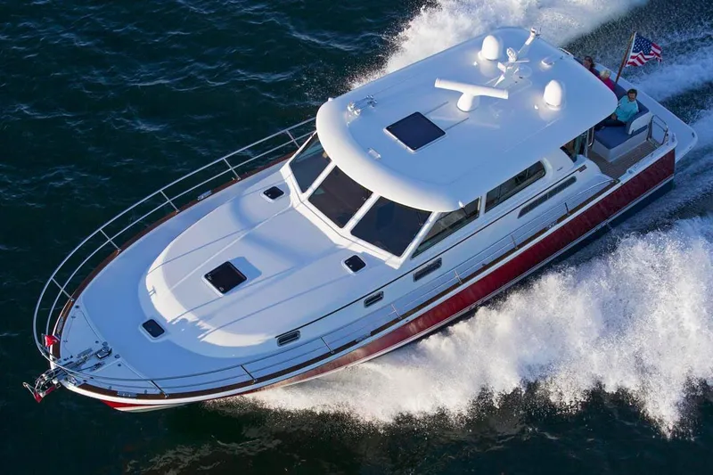 Slide: The Image of 2026 Sabre 45 Salon Express yacht cruising with passengers, American flag displayed, scenic coastal backdrop. - 3